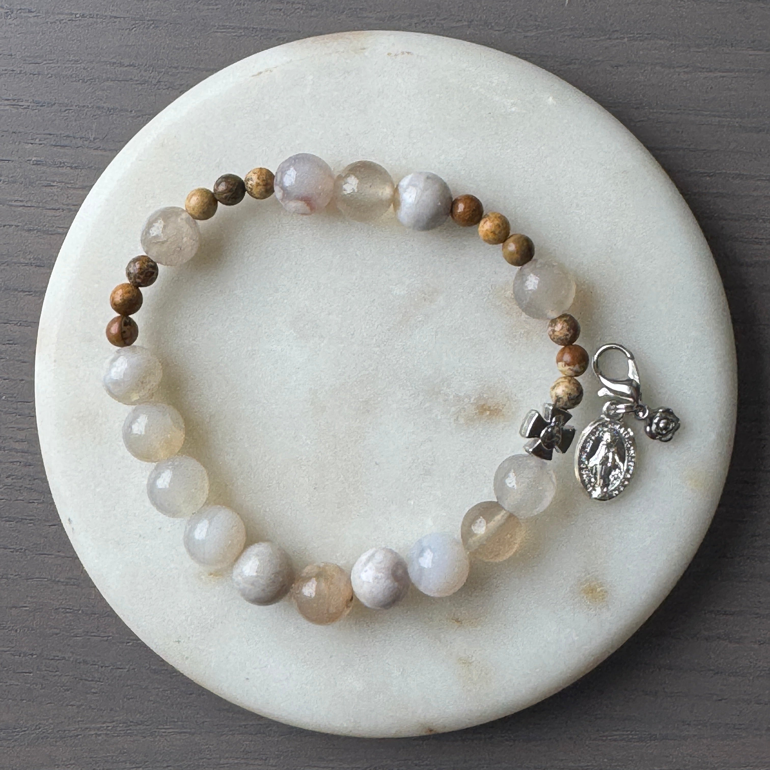 Creme gemstone bracelet with a silver clasp on a marble coaster