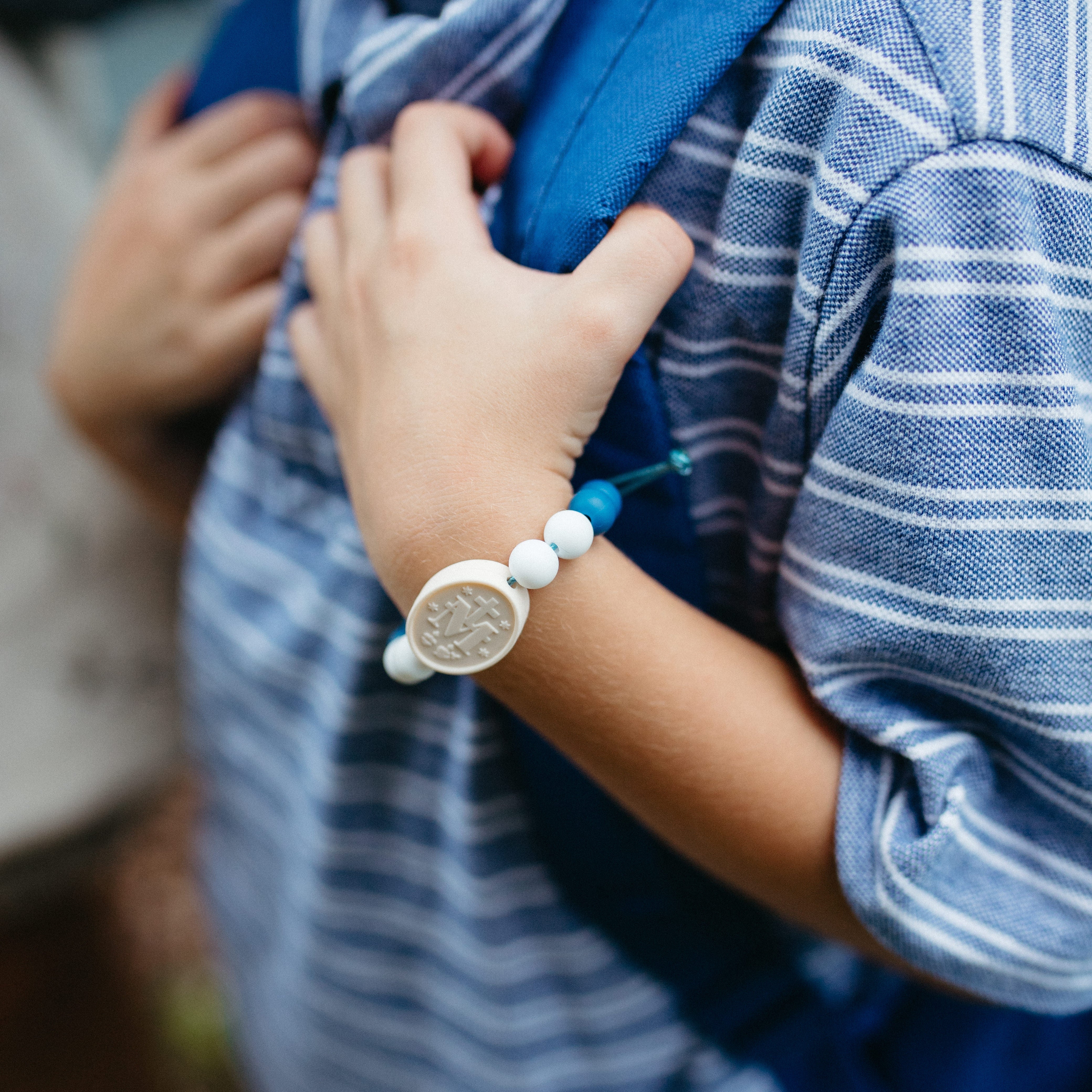 Child wearing a blue, white and ivory beaded silicone bracelet on blu paracord