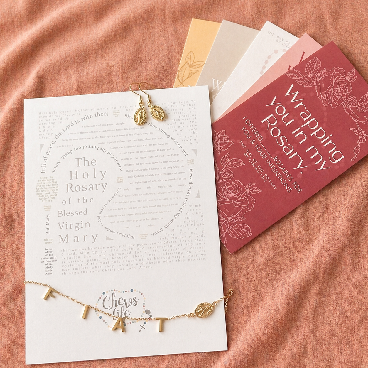 gold neckalce and earrings with stationary on pink background