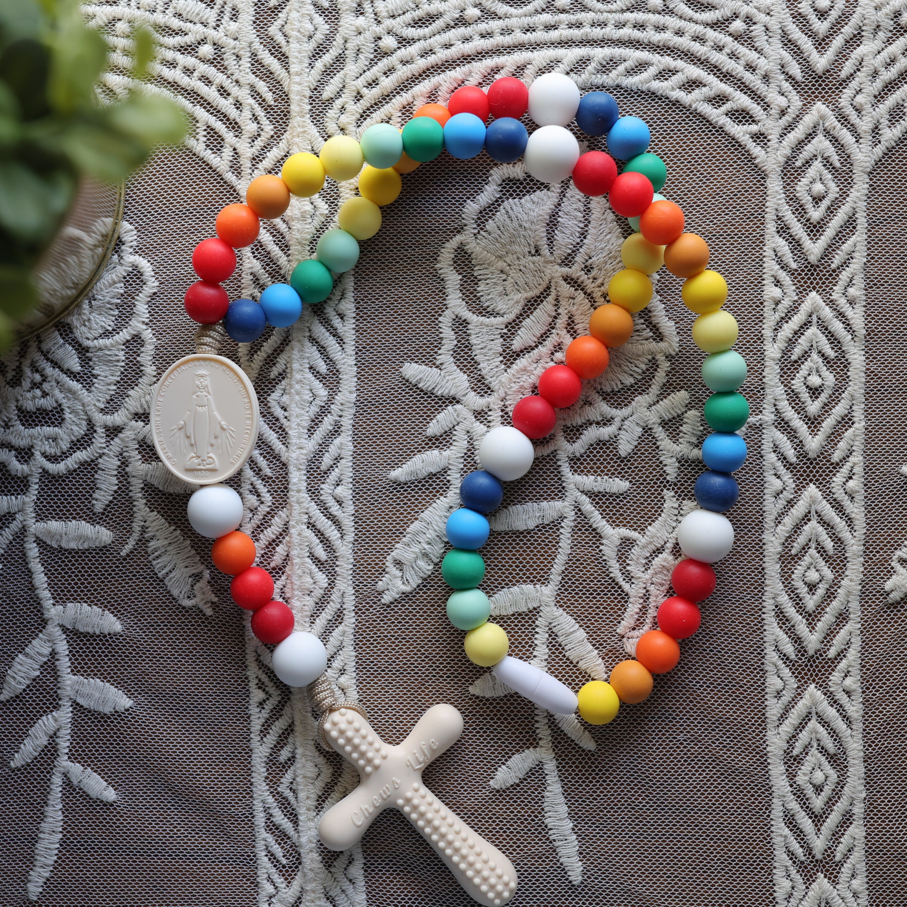 Colorful silicone rainbow rosary on a textured fabric background