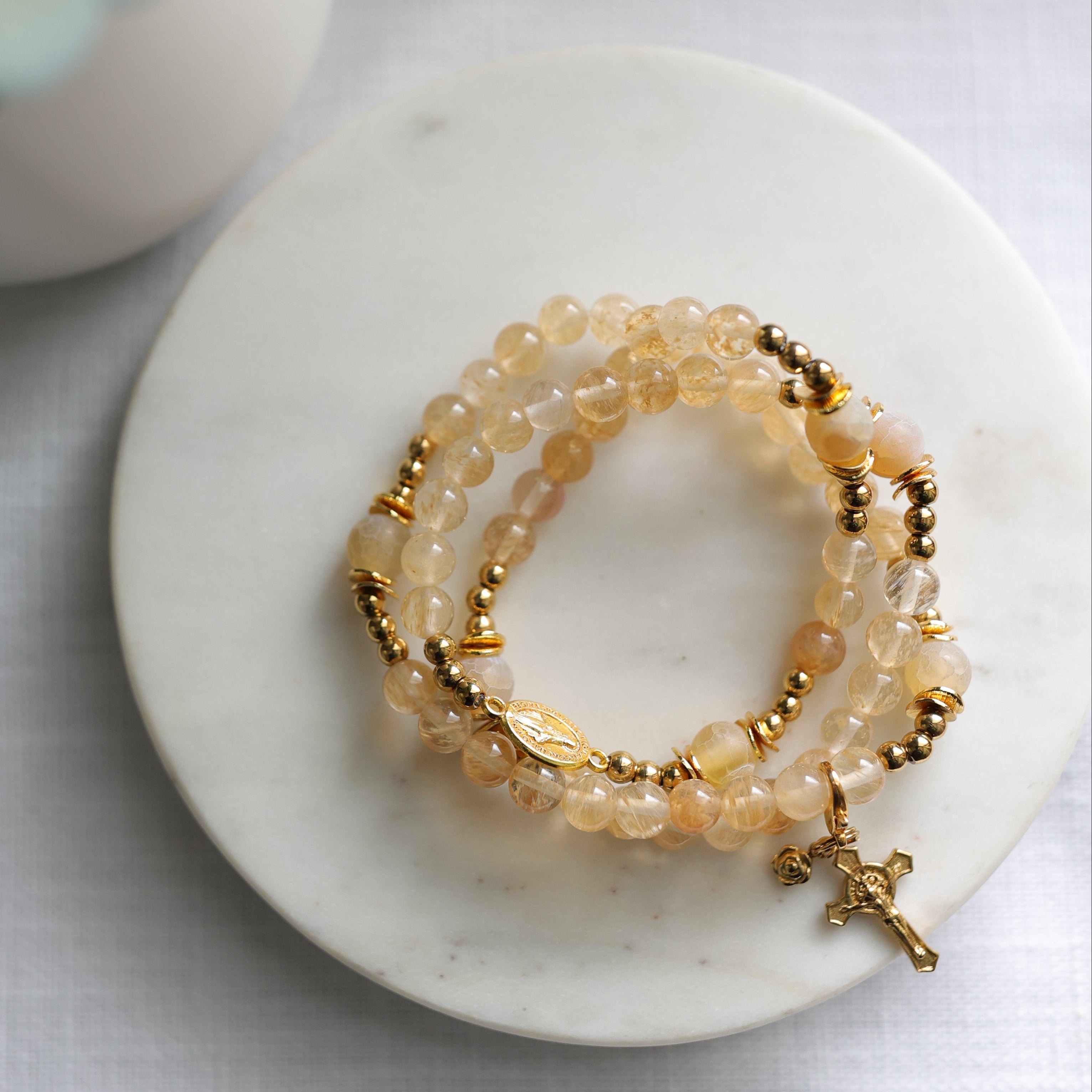 Rosary bracelet wrapped three times and laying on  a marble surface with a blurred background