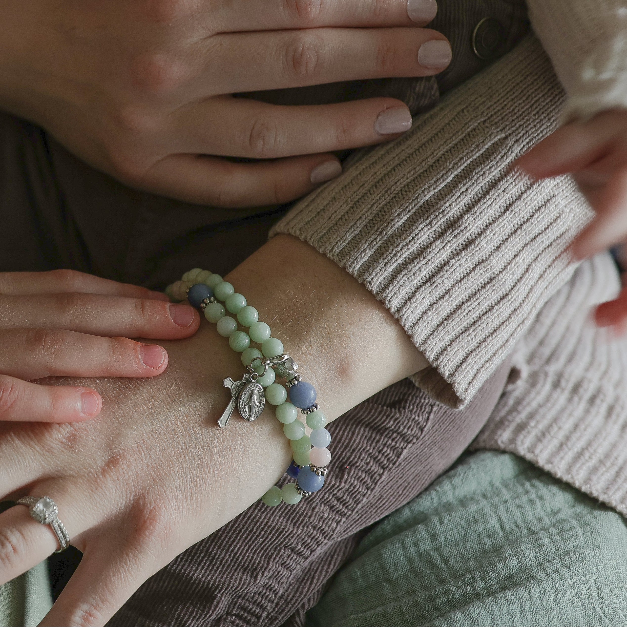 Two pairs of hands, one adult and one child, wearing bracelets, with a focus on the wrists.